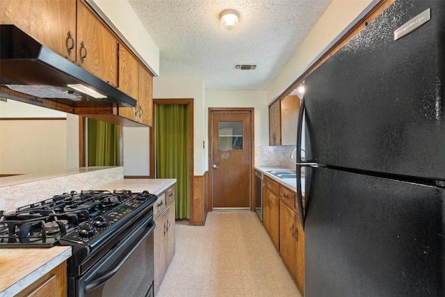 1012 Chesapeake Dr, Austin, TX 78758 - kitchen with black appliances, under cabinet range hood, light flooring, brown cabinetry, and light countertops
