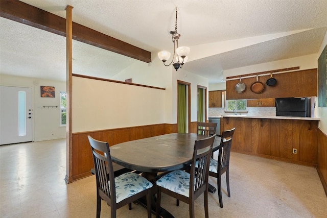 1012 Chesapeake Dr, Austin, TX 78758 - dining room with a wainscoted wall, a chandelier, wooden walls, light floors, and a textured ceiling
