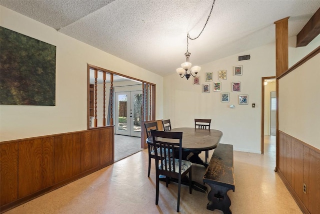 1012 Chesapeake Dr, Austin, TX 78758 - dining area featuring wainscoting, french doors, a textured ceiling, wood walls, and a chandelier