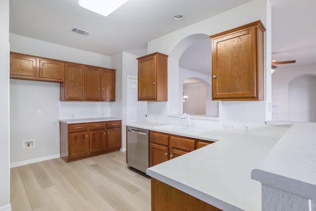 14943 Doria Dr, Austin, TX 78728 - kitchen with stainless steel dishwasher, light wood finished floors, brown cabinetry, and arched walkways