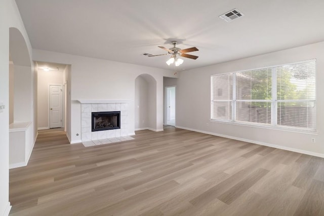 14943 Doria Dr, Austin, TX 78728 - unfurnished living room with arched walkways, ceiling fan, light wood finished floors, a tile fireplace, and baseboards
