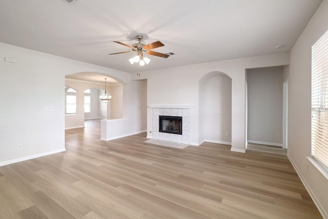 14943 Doria Dr, Austin, TX 78728 - unfurnished living room with arched walkways, a fireplace, ceiling fan, light wood-style floors, and baseboards