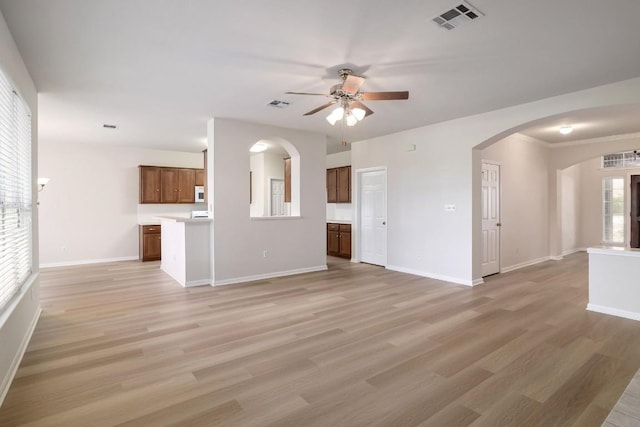 14943 Doria Dr, Austin, TX 78728 - unfurnished living room with a ceiling fan, arched walkways, light wood-type flooring, and baseboards
