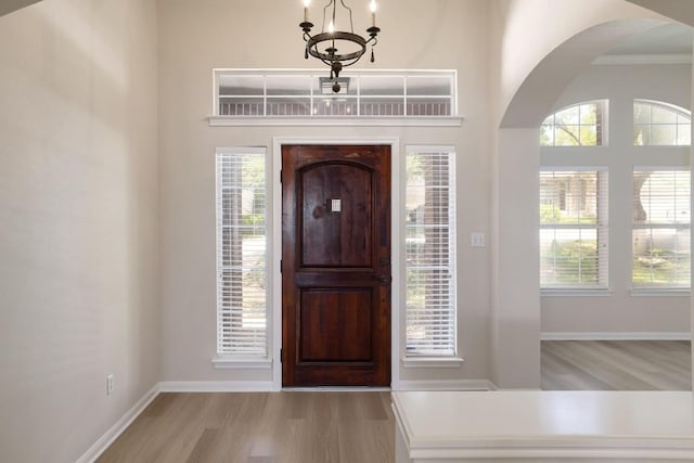 14943 Doria Dr, Austin, TX 78728 - foyer entrance with arched walkways, light wood-style flooring, a chandelier, baseboards, and crown molding