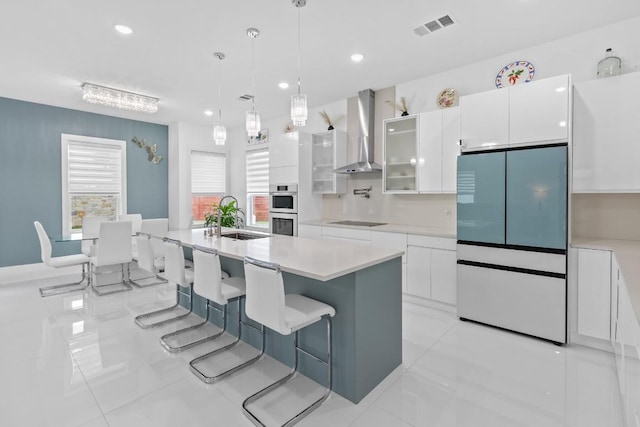 123 Zacate St, Elgin, TX 78621 - kitchen with wall chimney range hood, white fridge, black electric stovetop, white cabinetry, and light countertops