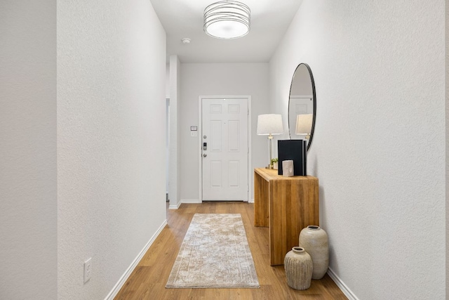107 Nathaniel Dr, Taylor, TX 76574 - doorway with light wood-type flooring, baseboards, and a textured wall
