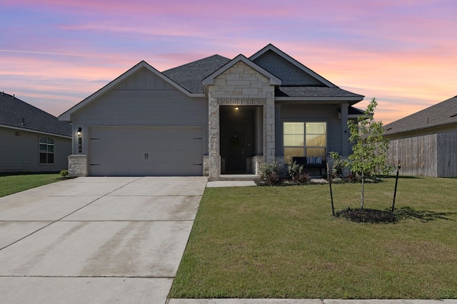 107 Nathaniel Dr, Taylor, TX 76574 - view of front of home with an attached garage, concrete driveway, a yard, stone siding, and a shingled roof