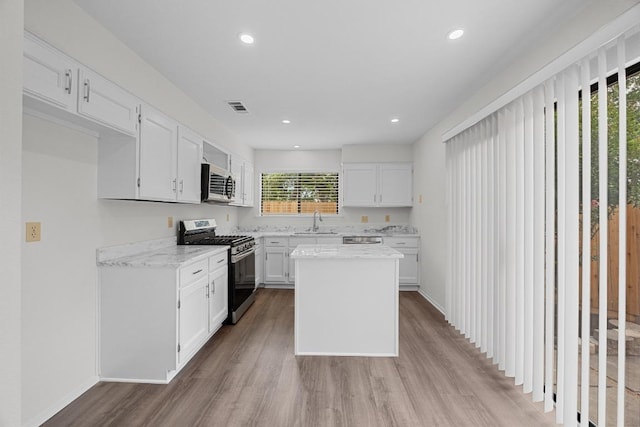 5225 Langwood Dr, Austin, TX 78754 - kitchen featuring appliances with stainless steel finishes, a sink, wood finished floors, white cabinetry, and light stone countertops