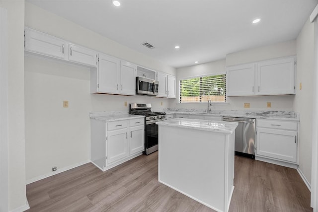 5225 Langwood Dr, Austin, TX 78754 - kitchen with stainless steel appliances, a sink, white cabinetry, light wood-type flooring, and light stone counters