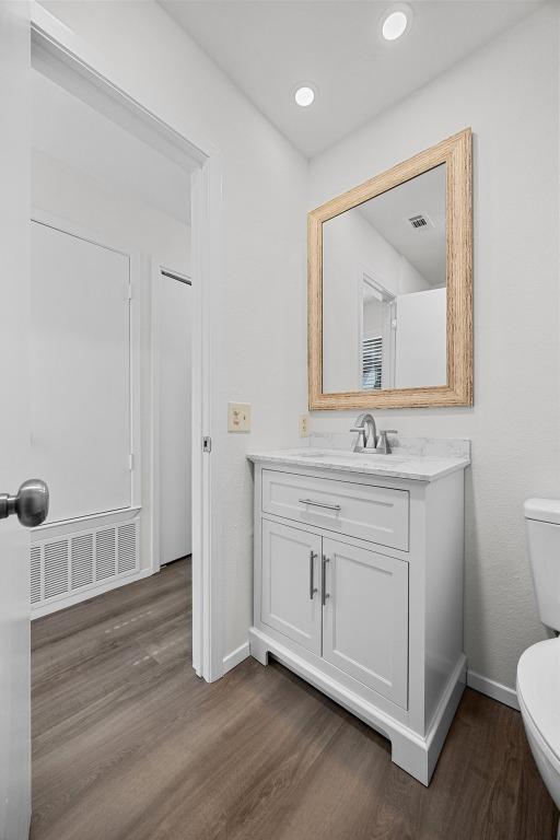 5225 Langwood Dr, Austin, TX 78754 - bathroom featuring toilet, wood finished floors, baseboards, vanity, and recessed lighting