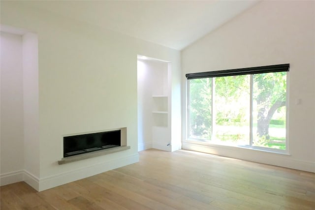 808 Vanguard St, Lakeway, TX 78734 - unfurnished living room with a fireplace with raised hearth, plenty of natural light, vaulted ceiling, and wood finished floors