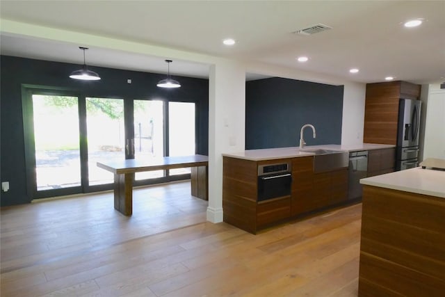 808 Vanguard St, Lakeway, TX 78734 - kitchen featuring appliances with stainless steel finishes, modern cabinets, brown cabinetry, light countertops, and hanging light fixtures
