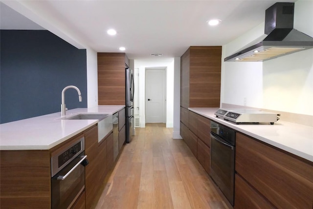 808 Vanguard St, Austin, TX 78734 - kitchen featuring modern cabinets, wall chimney range hood, stainless steel appliances, light wood-style floors, and light countertops