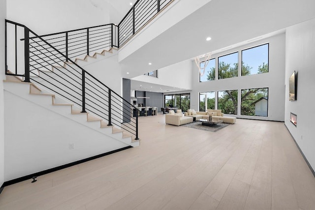 101 S Lake Hills Dr, Austin, TX 78733 - unfurnished living room with a towering ceiling, stairway, wood finished floors, and recessed lighting