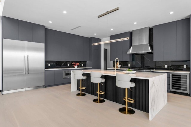 101 S Lake Hills Dr, Austin, TX 78733 - kitchen featuring beverage cooler, stainless steel appliances, wall chimney range hood, modern cabinets, and recessed lighting