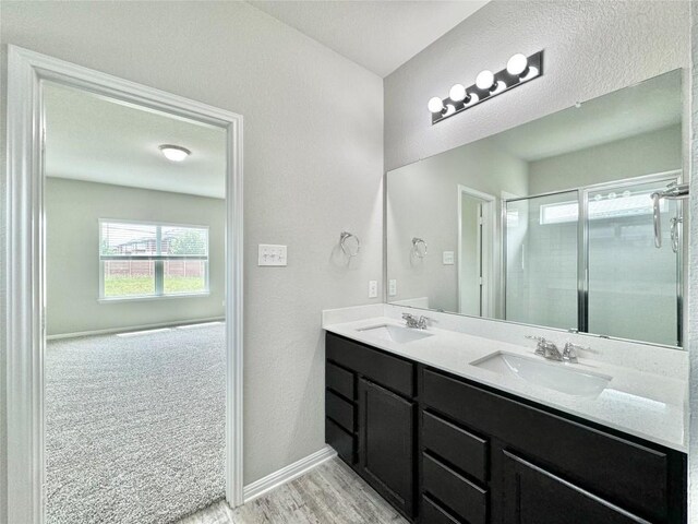 2721 Bridekirk Dr, Round Rock, TX 78664 - bathroom with double vanity, a stall shower, wood finished floors, and baseboards
