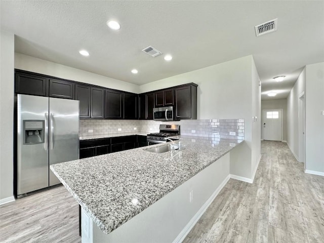 2721 Bridekirk Dr, Round Rock, TX 78664 - kitchen with stainless steel appliances, a peninsula, light wood finished floors, backsplash, and recessed lighting