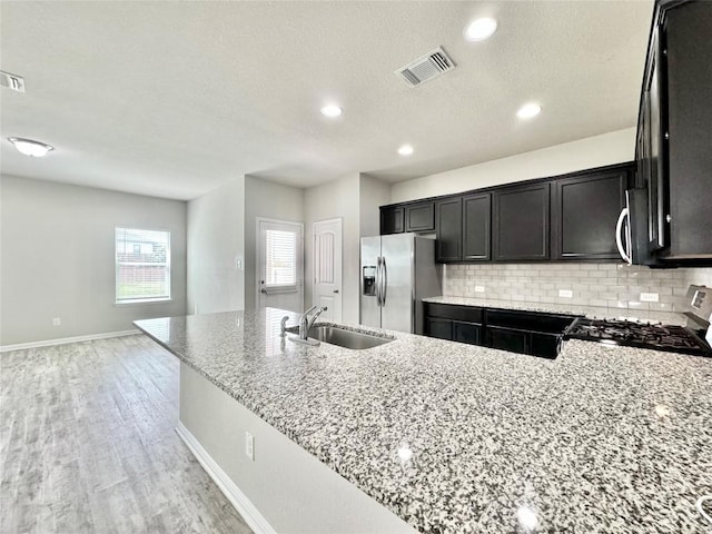 2721 Bridekirk Dr, Round Rock, TX 78664 - kitchen featuring stainless steel appliances, a sink, light stone counters, tasteful backsplash, and baseboards