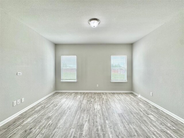 2721 Bridekirk Dr, Round Rock, TX 78664 - unfurnished room with wood finished floors, plenty of natural light, baseboards, a textured ceiling, and a textured wall