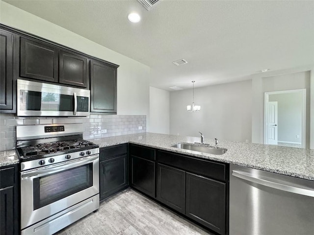 2721 Bridekirk Dr, Round Rock, TX 78664 - kitchen with stainless steel appliances, a sink, backsplash, light wood-style floors, and light stone countertops