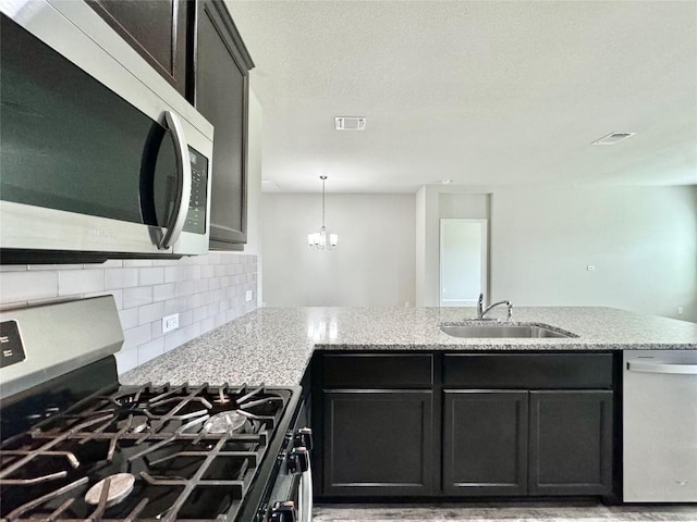 2721 Bridekirk Dr, Round Rock, TX 78664 - kitchen with appliances with stainless steel finishes, a sink, decorative backsplash, light stone countertops, and a peninsula