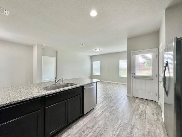 2721 Bridekirk Dr, Round Rock, TX 78664 - kitchen with stainless steel appliances, a sink, light wood-type flooring, dark cabinets, and open floor plan