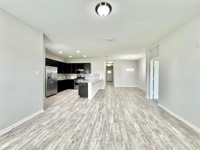 2721 Bridekirk Dr, Round Rock, TX 78664 - kitchen with stainless steel appliances, open floor plan, dark cabinets, light wood-style flooring, and light countertops