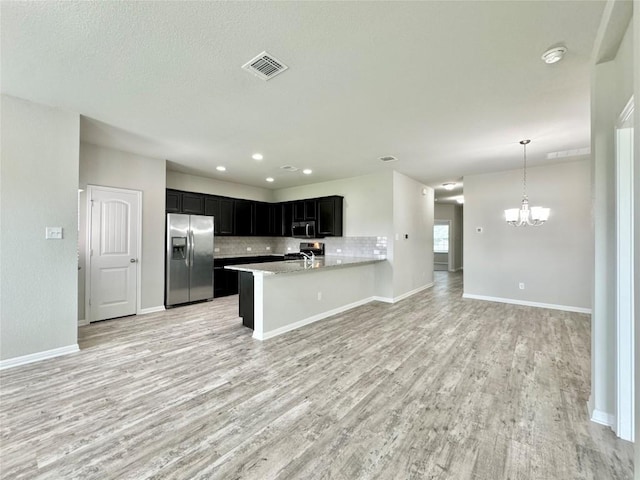 2721 Bridekirk Dr, Round Rock, TX 78664 - kitchen featuring stainless steel appliances, open floor plan, light wood-style flooring, dark cabinetry, and a chandelier