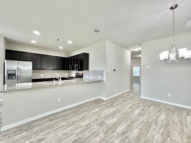 2721 Bridekirk Dr, Round Rock, TX 78664 - kitchen with appliances with stainless steel finishes, light wood-type flooring, tasteful backsplash, a sink, and light stone countertops