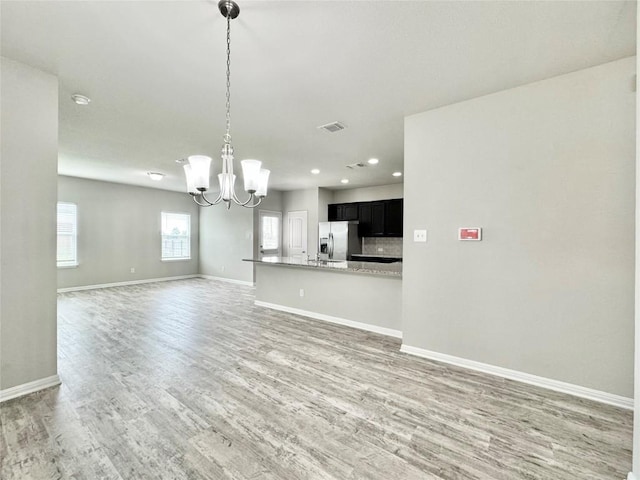 2721 Bridekirk Dr, Round Rock, TX 78664 - unfurnished living room with a chandelier, light wood-style floors, baseboards, and recessed lighting