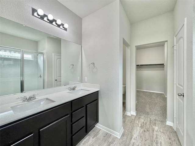 2721 Bridekirk Dr, Round Rock, TX 78664 - bathroom featuring double vanity, a stall shower, wood finished floors, toilet, and baseboards