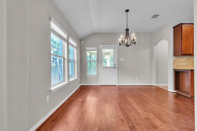 204 Chickadee Ln, Leander, TX 78641 - unfurnished dining area with wood finished floors, a chandelier, vaulted ceiling, arched walkways, and baseboards