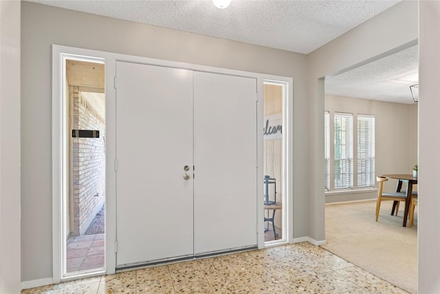 12701 Poquoson Dr, Austin, TX 78727 - foyer entrance featuring a textured ceiling, baseboards, and light carpet