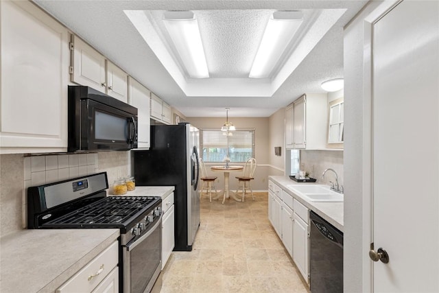 12701 Poquoson Dr, Austin, TX 78727 - kitchen with black appliances, a tray ceiling, a sink, backsplash, and light countertops