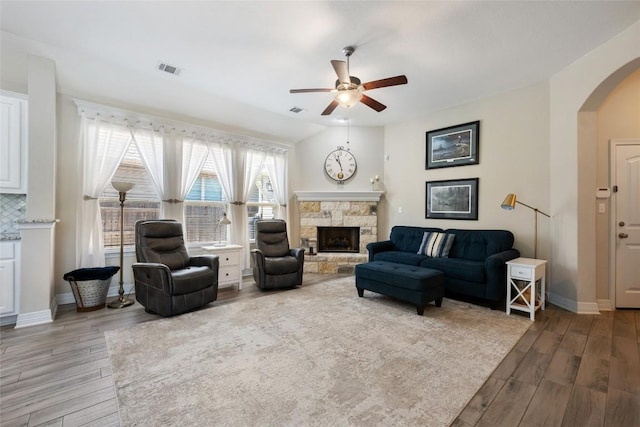 213 Russet Trl, Georgetown, TX 78628 - living room featuring arched walkways, a ceiling fan, light wood-style floors, and a fireplace