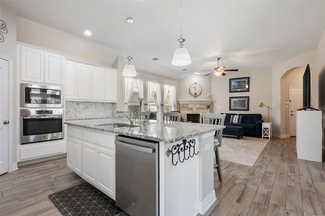 213 Russet Trl, Georgetown, TX 78628 - kitchen featuring appliances with stainless steel finishes, a sink, arched walkways, light wood finished floors, and open floor plan