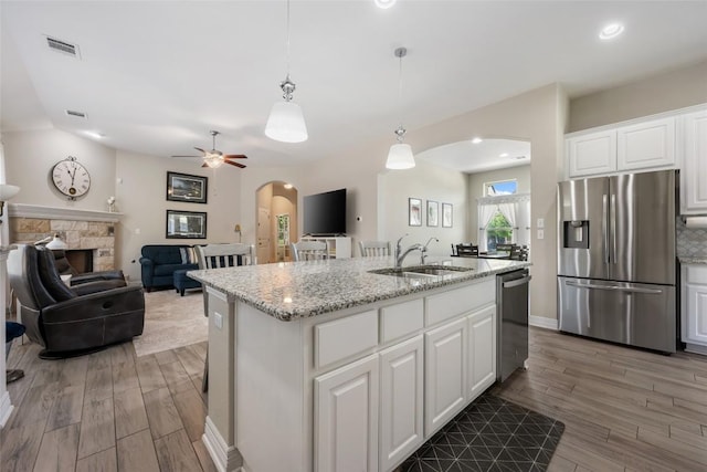 213 Russet Trl, Georgetown, TX 78628 - kitchen featuring stainless steel appliances, a sink, arched walkways, wood finished floors, and white cabinetry