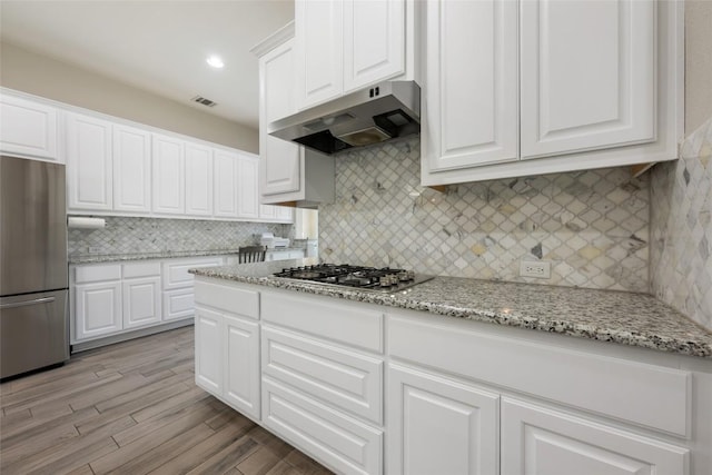 213 Russet Trl, Georgetown, TX 78628 - kitchen with under cabinet range hood, appliances with stainless steel finishes, white cabinets, and tasteful backsplash