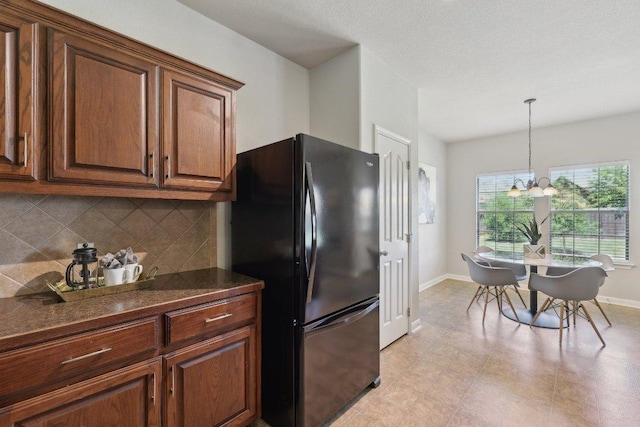 1207 Tricia Cv, Hutto, TX 78634 - kitchen featuring freestanding refrigerator, dark countertops, backsplash, and baseboards