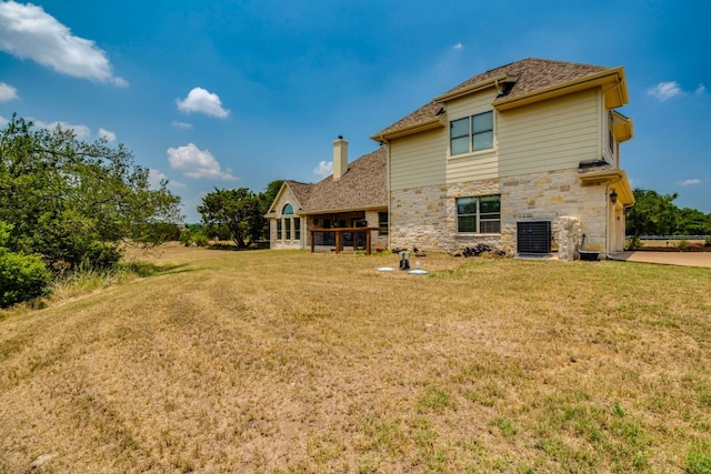421 Huck Finn Trl, Dripping Springs, TX 78620 - rear view of property featuring stone siding, a lawn, and central AC