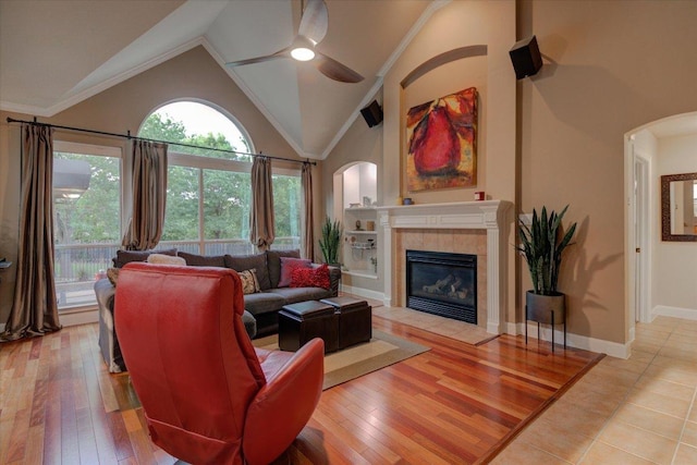 9508 Bully Hill Cv, Austin, TX 78759 - living area featuring arched walkways, a tiled fireplace, ceiling fan, high vaulted ceiling, and light wood-type flooring