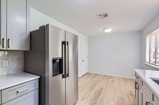 11306 Thorny Brook Trl, Austin, TX 78750 - kitchen featuring stainless steel fridge, light wood-style floors, backsplash, light countertops, and baseboards