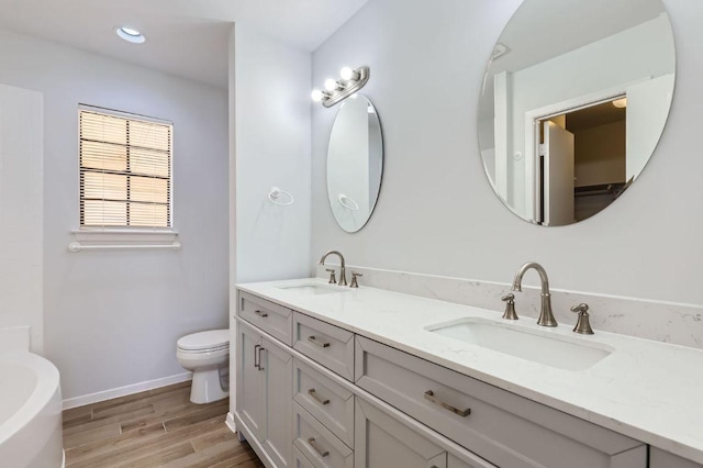 11306 Thorny Brook Trl, Austin, TX 78750 - full bathroom with double vanity, toilet, a tub, wood finished floors, and baseboards