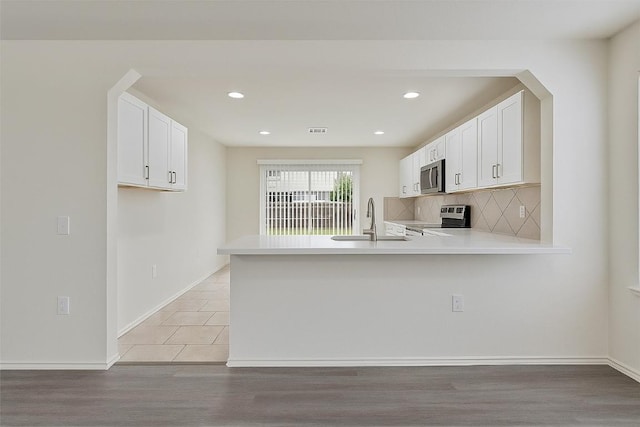 7432 Cayenne Ln, Austin, TX 78741 - kitchen featuring appliances with stainless steel finishes, a sink, light countertops, light wood-style flooring, and recessed lighting