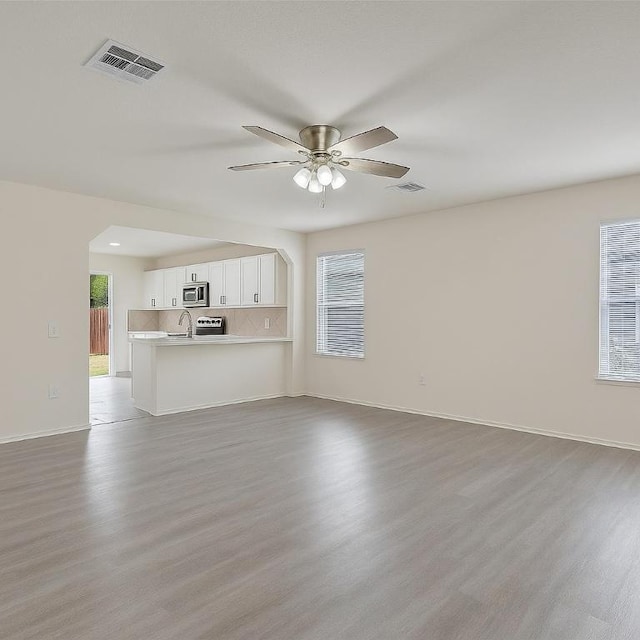 7432 Cayenne Ln, Austin, TX 78741 - unfurnished living room with light wood-style floors, ceiling fan, baseboards, and a sink