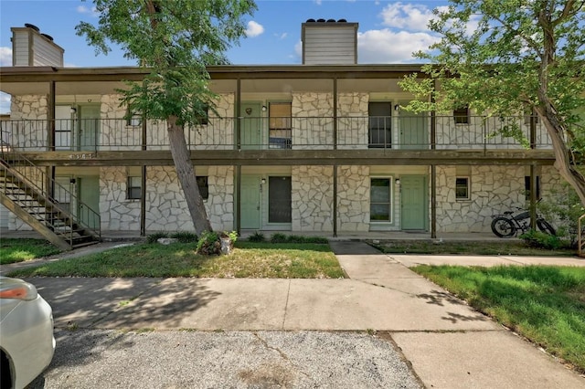 4307 S 1st St Unit 104, Austin, TX 78745 - view of front of house with stone siding, a chimney, stairway, and a balcony