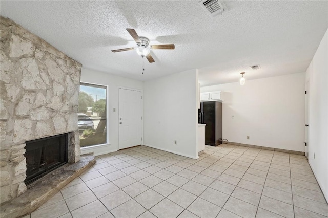 4307 S 1st St Unit 104, Austin, TX 78745 - unfurnished living room with a ceiling fan, a textured ceiling, a fireplace, and light tile patterned floors