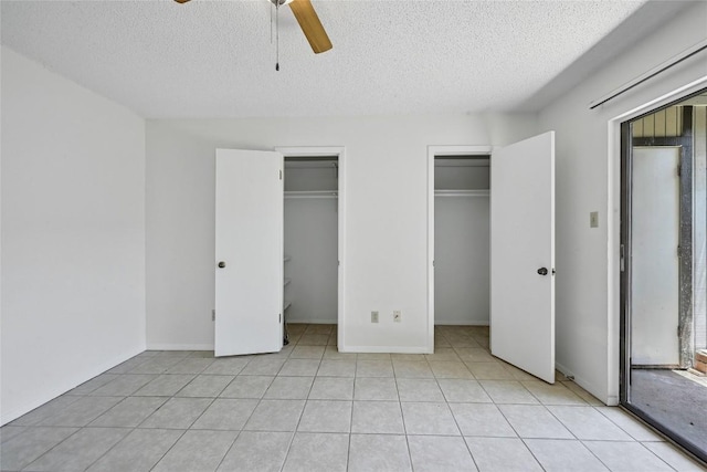 4307 S 1st St Unit 104, Austin, TX 78745 - unfurnished bedroom featuring a textured ceiling, two closets, a ceiling fan, and light tile patterned flooring