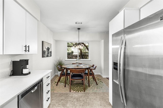 12225 Mosley Ln, Austin, TX 78727 - kitchen featuring stainless steel appliances, light countertops, white cabinetry, and hanging light fixtures