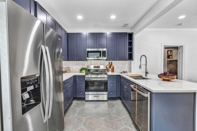803 Josephine St, Austin, TX 78704 - kitchen featuring appliances with stainless steel finishes, a sink, a peninsula, light tile patterned flooring, and decorative backsplash